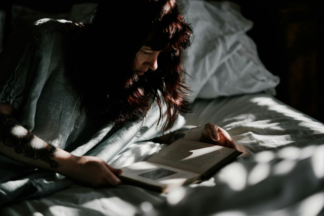 woman reading book on bed