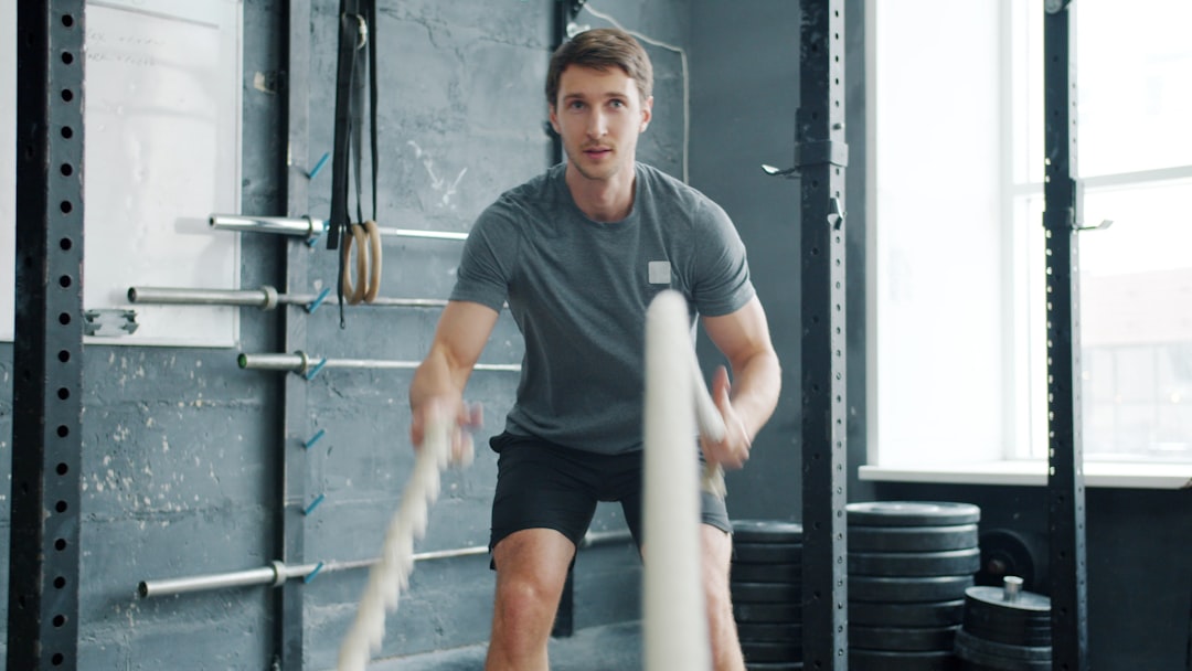 Man exercising with battle ropes in gym