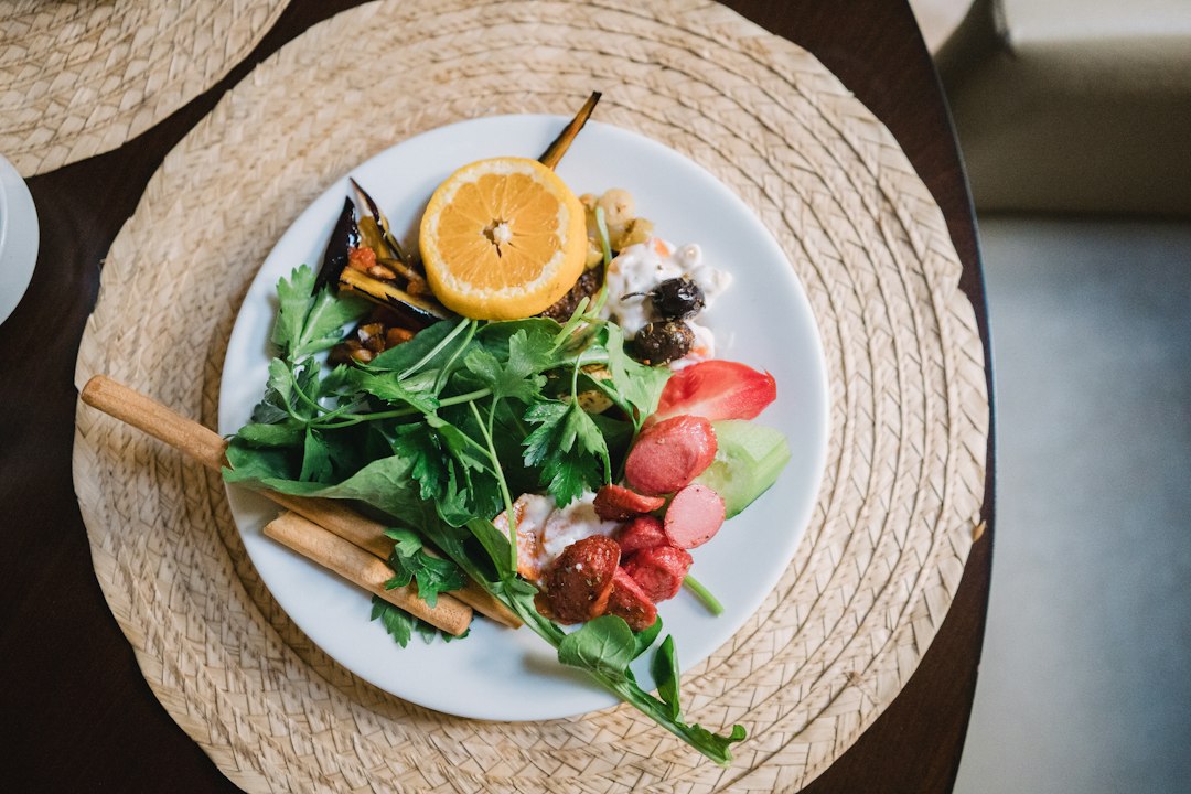 A white plate topped with a salad next to a cup of coffee